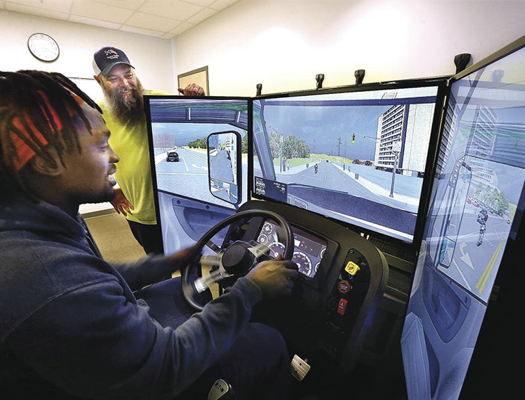 image of student using trucking simulator, instructor watching