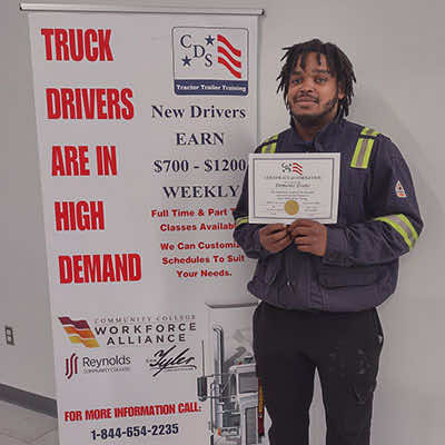 image of CDS grad, Demonte Evans, posing with his certificate