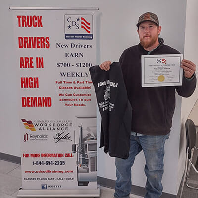 Image of CDS grad, Nicholas Brown, posing with his certificate and shirt