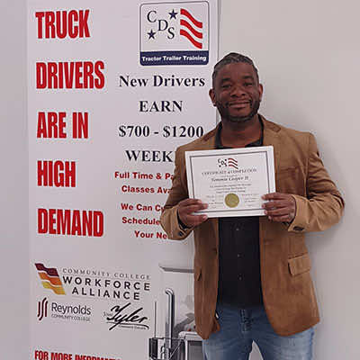 Image of CDS grad, Tommy Cooper II, posing with his certificate
