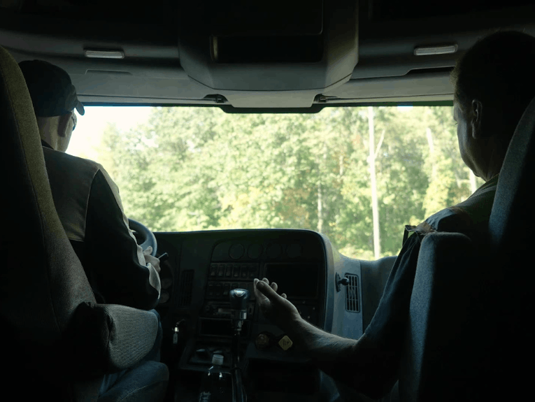 Two truckers sitting in semi truck, behind the head view