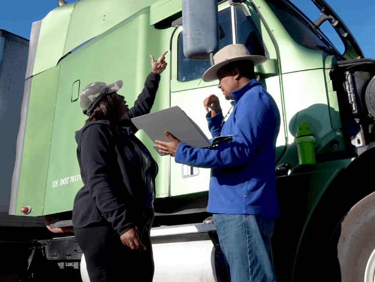 CDS student pointing at semi truck mirror, instructor standing with clipboard